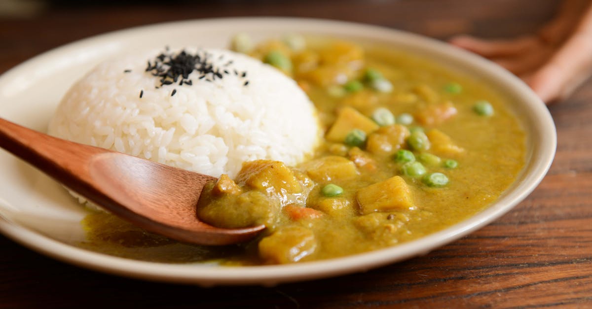 A delicious plate of creamy vegetable curry served with rice and a wooden spoon, perfect for a tasty meal.